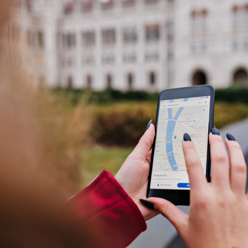 Woman with trendy manicure using gps for search right way. Photo of female hands with smartphone.